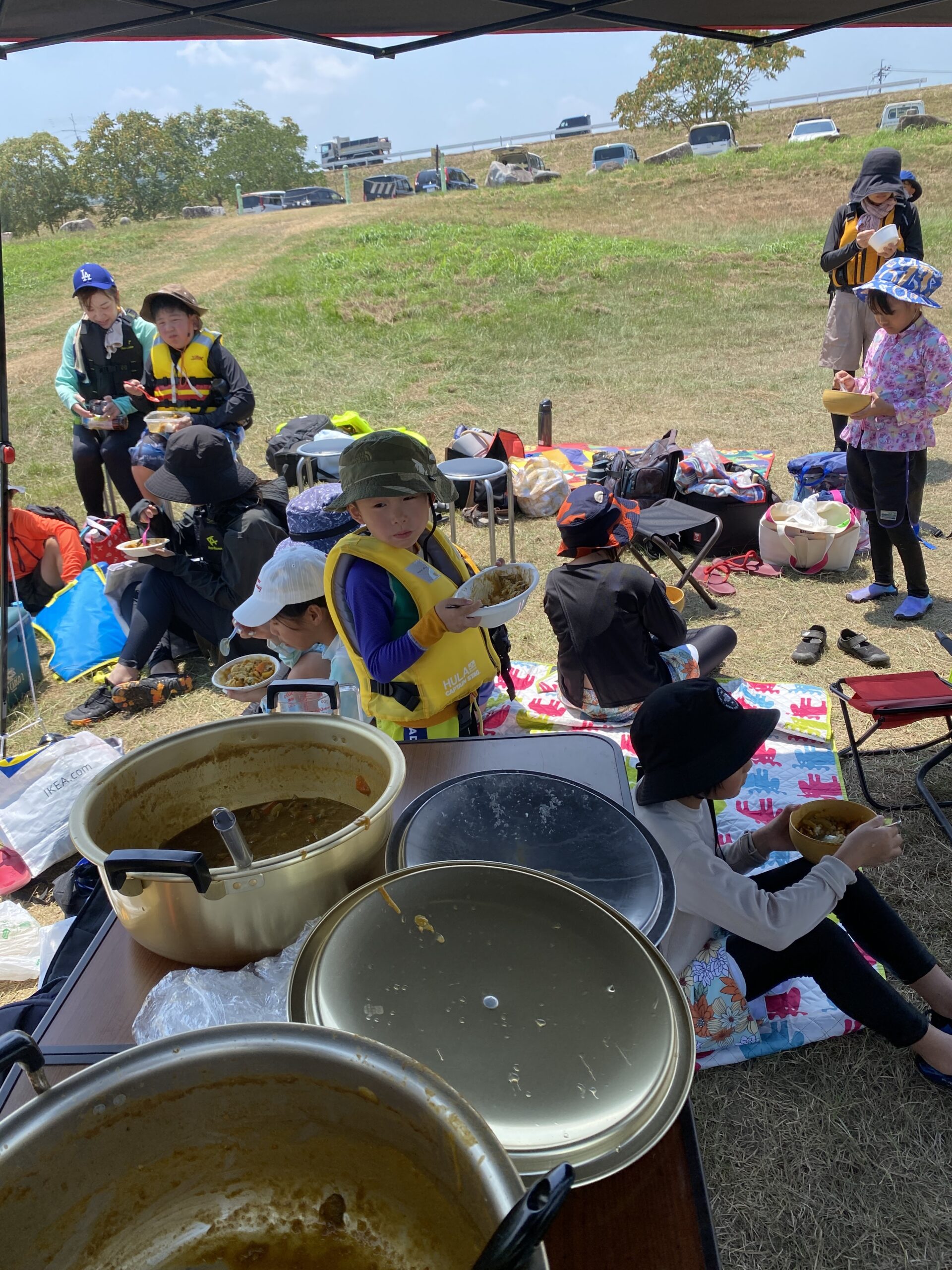 テントの下でスコレー米と桃の特製カレーを味わう参加者